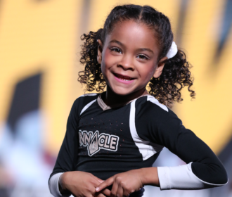 Youth cheerleader smiles at the camera during a performance