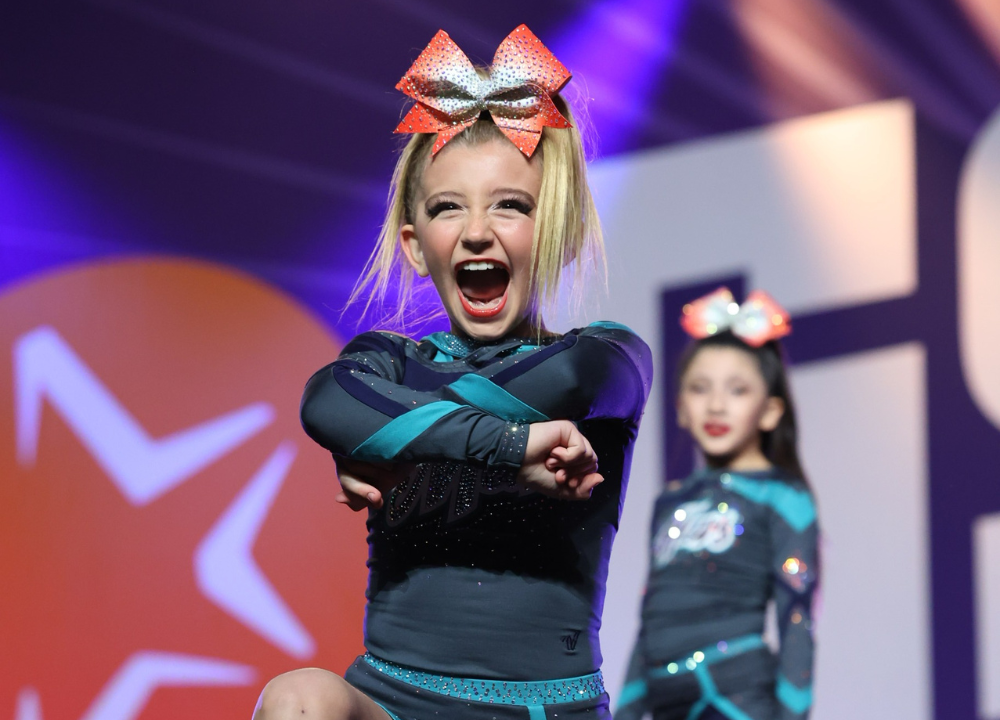 All star cheerleader with a big smile crosses her arms during a routine