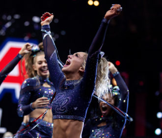 Cheerleader celebrating with arms in air in confetti at NCA All Star nationals