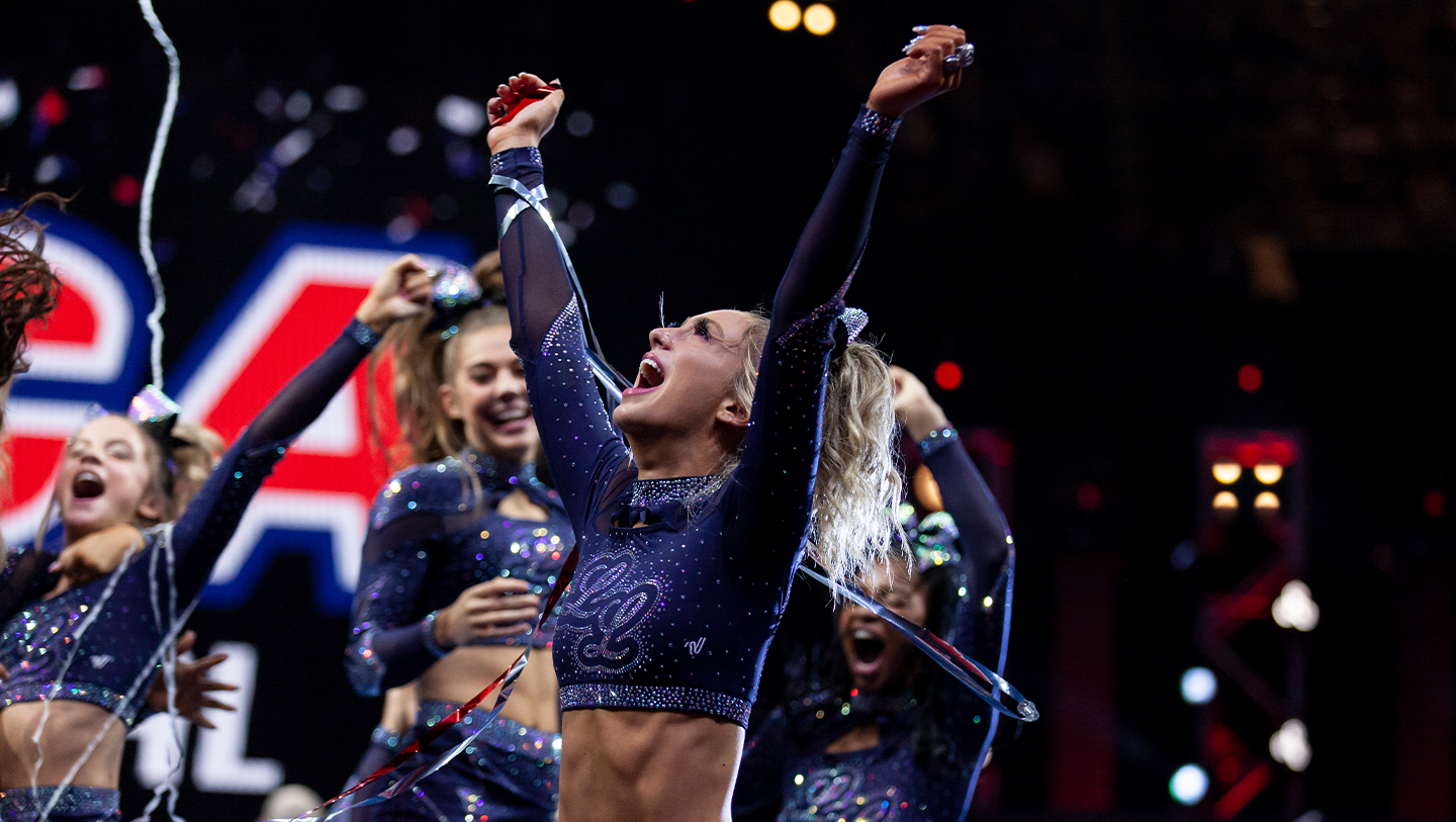 Cheerleader celebrating with arms in air in confetti at NCA All Star nationals