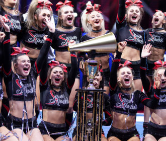 Cheerleaders celebrating with trophy and confetti at NCA All Star Nationals